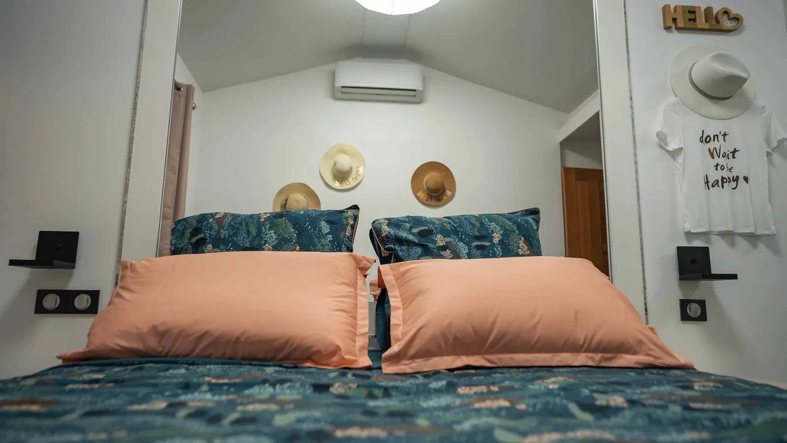 Chambre Caraïbeen Lady — les chapeaux de paille au mur, vus depuis les coussins