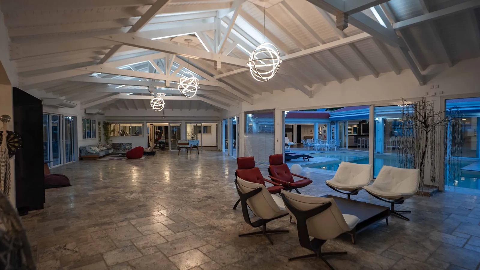 La grande salle de House of Harmony le soir, lampes-sphères allumées et piscine éclairée