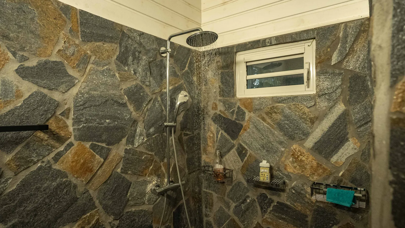 Pavillon Bubble Blue Wave — douche de pluie sur mur de pierre