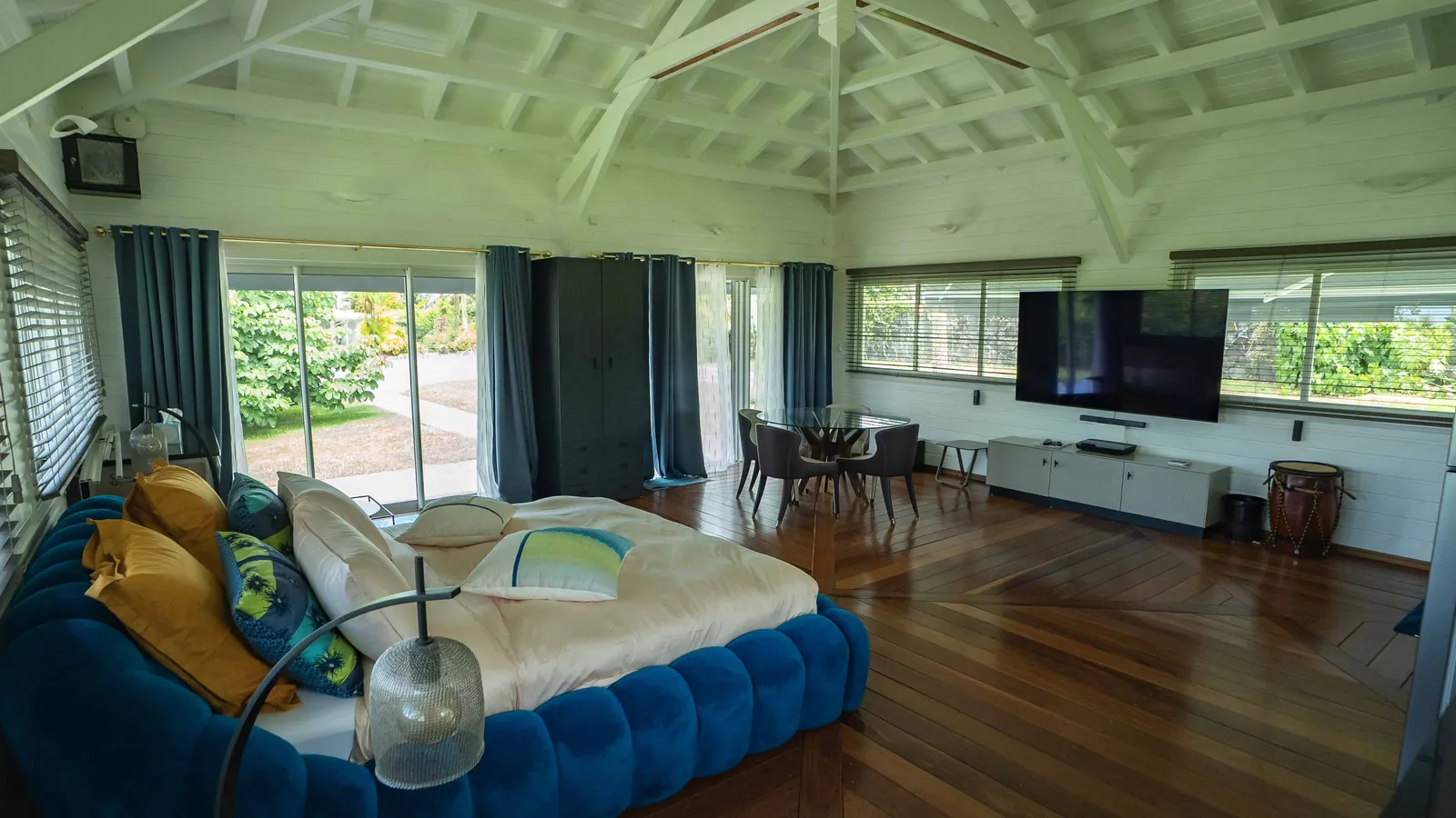 Pavillon Bubble Blue Wave — le lit, la table de repas et le grand écran, baies sur le jardin